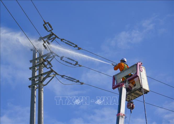 Công nhân Điện lực Mường Chà (tỉnh Điện Biên) rửa sứ hotline. Ảnh: Xuân Tư – TTXVN