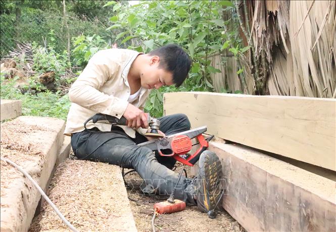 Thanh niên người Ơ Đu ở bản Văng Môn (xã Nga My, huyện Tương Dương) sửa bào nhẵn cột gỗ để dựng nhà ở. Ảnh: Xuân Tiến - TTXVN 