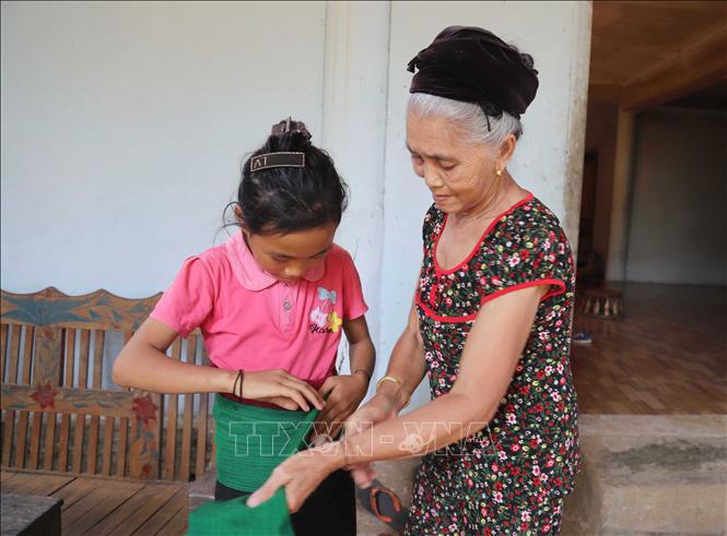 Bà Vi Thị Dung hướng dẫn cách mặc trang phục truyền thống cho thế hệ trẻ. Ảnh: Xuân Tiến - TTXVN 