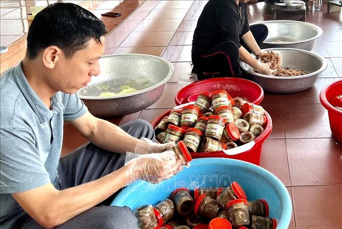 Dán nhãn cho món thịt chua đu đủ. Ảnh: Tạ Toàn - TTXVN