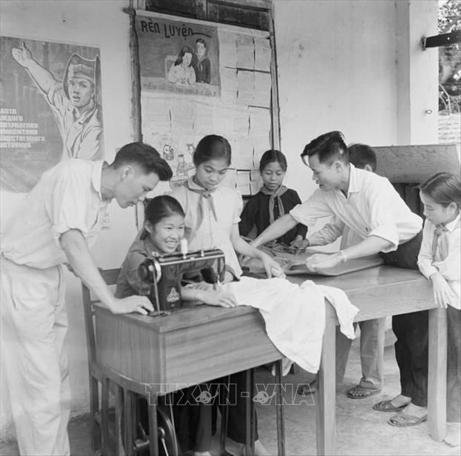 Giáo viên trường Phổ thông cấp I dân lập cọc 5 Hòn Gai hướng dẫn học sinh cắt và may quần áo (5/1963). Ảnh: TTXVN