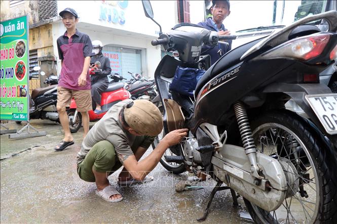 Người dân sửa lại xe máy bị hư hỏng do ngập trong nước. Ảnh: Đỗ Trưởng - TTXVN