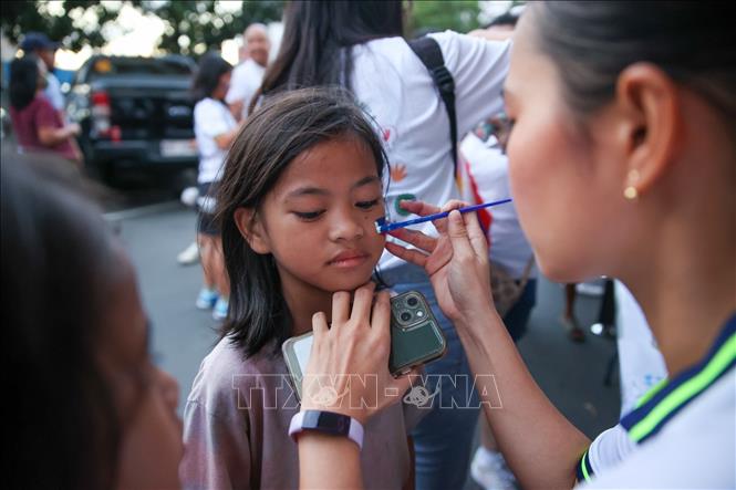 Một em bé Philippines đang được vẽ quốc kỳ trên mặt ở bên ngoài sân Rizal. Ảnh: Hoàng Linh/TTXVN