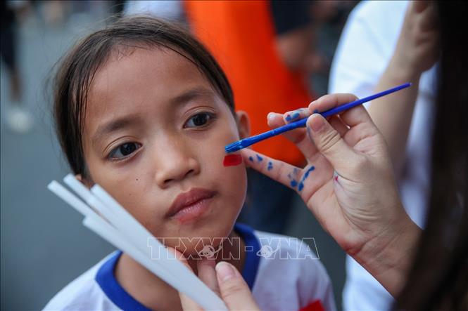 Một em bé Philippines đang được vẽ quốc kỳ trên mặt ở bên ngoài sân Rizal. Ảnh: Hoàng Linh/TTXVN