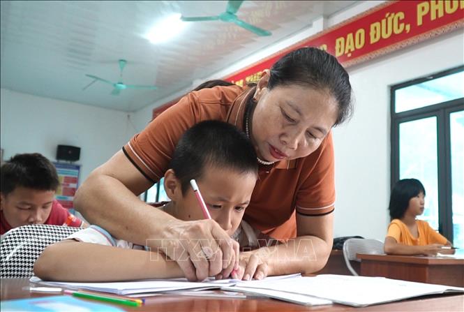 Mặc dù đã nghỉ hưu nhưng cô giáo Hoàng Thị Vỵ (người dân tộc Cao Lan ở thôn Ngòi Khang, xã Bảo Ái, huyện Yên Bình, tỉnh Yên Bái) vẫn tiếp tục dạy chữ và hỗ trợ chăm sóc trẻ bị khuyết tật. Ảnh: Việt Dũng - TTXVN