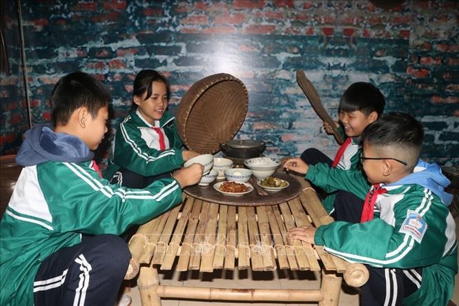 Học sinh trải nghiệm mâm cơm thời bao cấp. Ảnh: Mạnh Minh - TTXVN