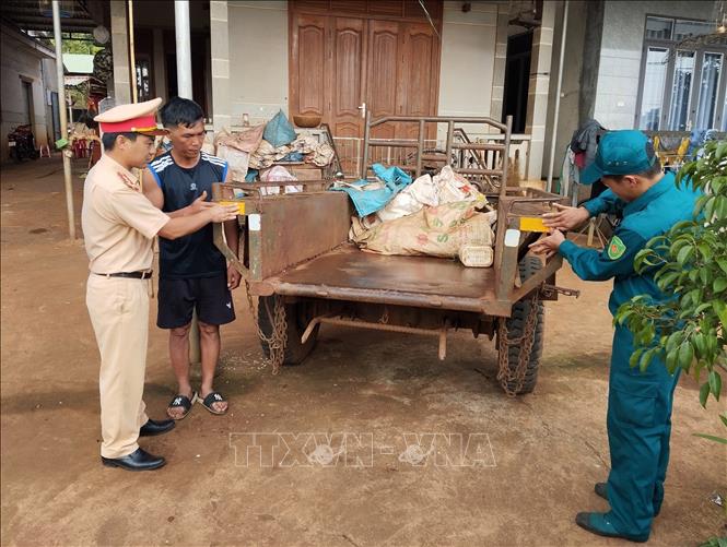 Lực lượng công an, dân quân đến tận nhà để dán đề can phản quang cho xe công nông của người dân. Ảnh: TTXVN phát
