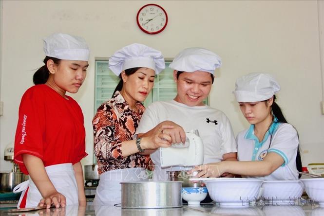 Giáo viên hướng dẫn trẻ khuyết tật (khiếm thính, khiếm thị) đánh bột làm các loại bánh tại Trung tâm Bảo trợ xã hội tỉnh Khánh Hòa, nhằm giúp các em có nghề và việc làm sau khi được đào tạo. Ảnh: Phan Sáu - TTXVN