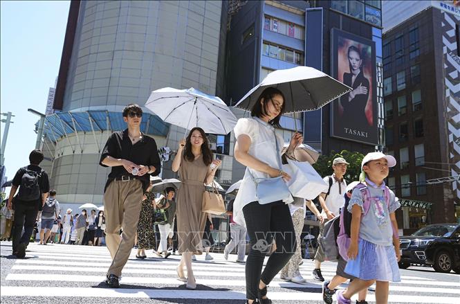 Người dân che ô tránh nắng nóng trên đường phố tại Tokyo, Nhật Bản. Ảnh: Kyodo/TTXVN