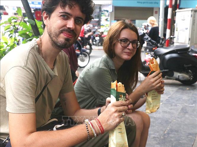 Du khách thưởng thức bánh mì truyền thống của Hà Nội trên phố Hàng Bông. Ảnh: Vũ Thanh - TTXVN phát