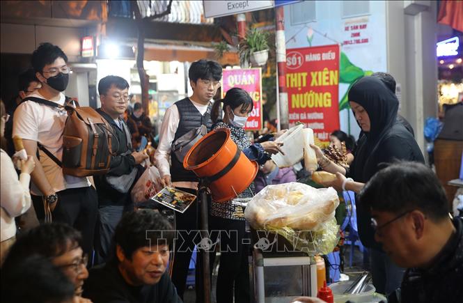Du khách chờ mua thịt xiên nướng, ăn với bánh mì trên phố Hàng Điếu, Hoàn Kiếm. Ảnh: Nguyễn Hoa - TTXVN phát
