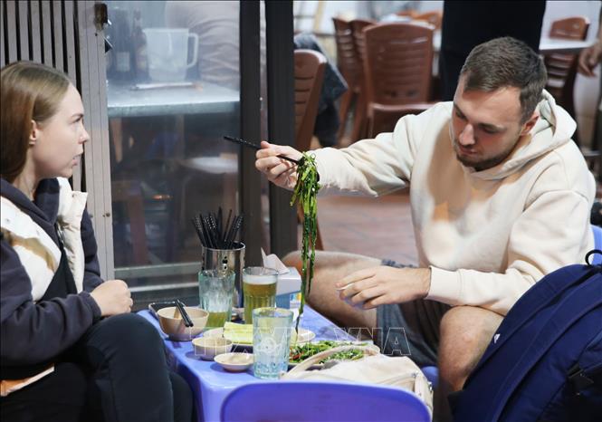 Du khách thưởng thức món rau muống xào, món ăn bình dị và rất phổ biến của Việt Nam. Ảnh: Nguyễn Hoa - TTXVN phát