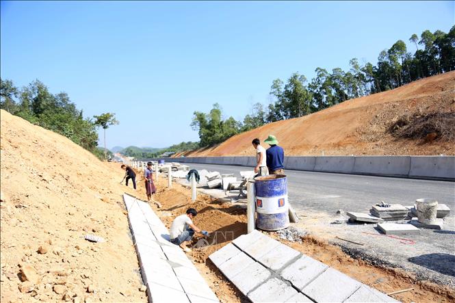 Lắp đặt dải phân cách giữa, thi công hàng rào bảo vệ ngăn với đường dân sinh, lắp đặt hộ lan đường, hoàn thiện hệ thống rãnh thoát nước. Ảnh: Vũ Quang - TTXVN