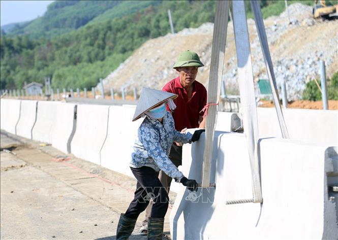 Lắp đặt dải phân cách giữa, thi công hàng rào bảo vệ ngăn với đường dân sinh, lắp đặt hộ lan đường, hoàn thiện hệ thống rãnh thoát nước. Ảnh: Vũ Quang - TTXVN