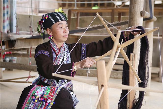 Xe sợi một trong những khâu vất vả đòi hỏi sự tỉ mỉ trước khi dệt ra những tấm vải thổ cẩm để may váy, áo. Ảnh: Quý Trung – TTXVN