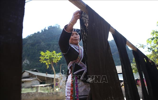 Vải được phơi trong nắng, người phụ nữ Lự phải căng vải sao cho không bị nhăn tránh bị phai màu. Ảnh: Quý Trung – TTXVN