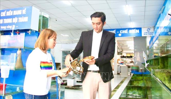Anh Thịnh giới thiệu sản phẩm hải sản với khách hàng. Ảnh: Võ Dung - TTXVN