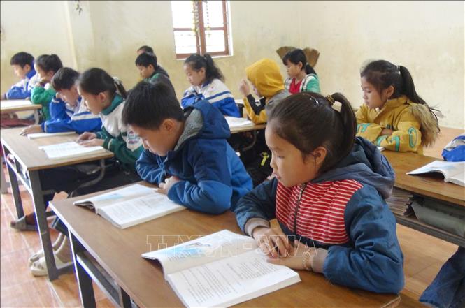 Tại lớp 5 điểm trường bản Na Ngân (Trường Tiểu học Nga My, huyện Tương Dương, tỉnh Nghệ An), giáo viên đã sắp xếp lại bàn ghế để các học sinh trong lớp ngồi gần nhau hơn nhằm giữ nhiệt cho học sinh. Ảnh: Xuân Tiến - TTXVN                        