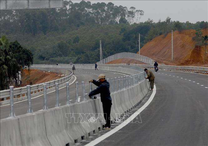 Công nhân đang lắp đặt dải phân cách giữa. Ảnh: Huy Hùng - TTXVN