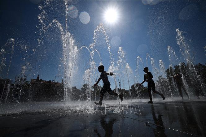 Trẻ em giải nhiệt tránh nóng tại đài phun nước ở Colmar, Pháp ngày 21/8/2023. Ảnh: AFP/TTXVN