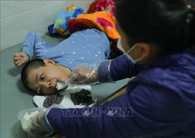 Với những nạn nhân không thể di chuyển, tự chăm sóc, nhân viên trung tâm đến từng giường phục vụ bữa ăn mỗi ngày. Ảnh: Hoàng Hiếu – TTXVN