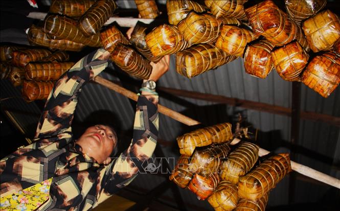 Bánh Tét sau khi luộc chín được treo lên sào, chờ nguội rồi phân chia cho những người tham gia gói bánh. Ảnh: Nguyễn Hằng - TTXVN