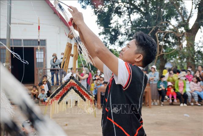 Đeo chuông gió lên cây nêu trước khi làm lễ để nhằm mục đích xua đuổi chim phá hoại mùa màng. Ảnh: Hoài Thu – TTXVN