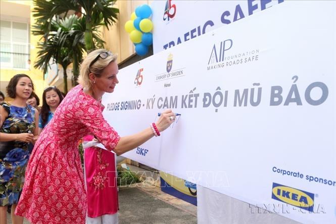 Bà Camila Melander, Đại sứ Thụy Điển tại Việt Nam và các đại biểu ký cam kết đội mũ bảo hiểm trong chương trình “Vui cùng giao thông” và tặng gần 500 mũ bảo hiểm cho các em học sinh khối lớp 2, trường Tiểu học Cát Linh (Hà Nội), 2014. Ảnh: Minh Quyết - TTXVN