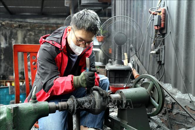Thợ chế tác tại xưởng mỹ nghệ Quyết Bình tạo hình chiếc lộc bình. Ảnh: Đức Hiếu - TTXVN