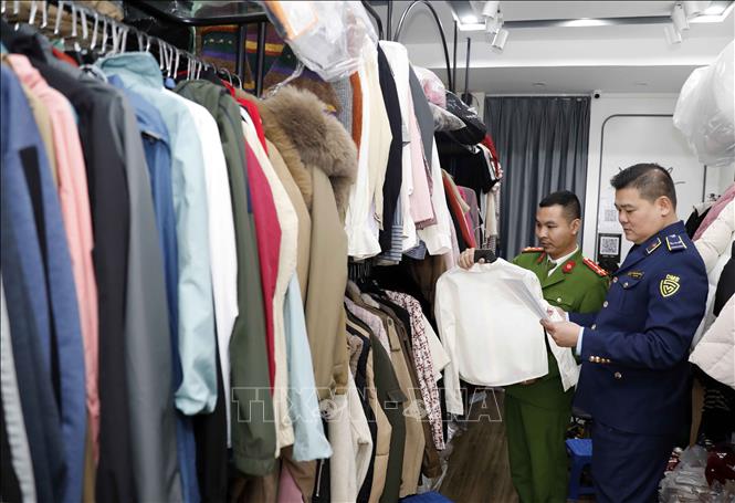 Tổ công tác Đội QLTT số 5, Cục QLTT Hà Nội phối hợp với Công an quận Hai Bà Trưng kiểm tra một hộ kinh doanh quần áo tại phố Bạch Mai, Hà Nội. Ảnh: Trần Việt - TTXVN