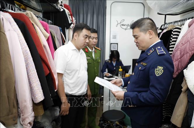 Tổ công tác Đội QLTT số 5, Cục QLTT Hà Nội phối hợp với Công an quận Hai Bà Trưng kiểm tra một hộ kinh doanh quần áo tại phố Bạch Mai, Hà Nội. Ảnh: Trần Việt - TTXVN