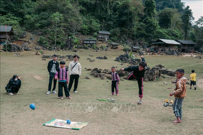 Tourists join with local children in spinning tops. VNA Photo: Phạm Tuấn Anh 