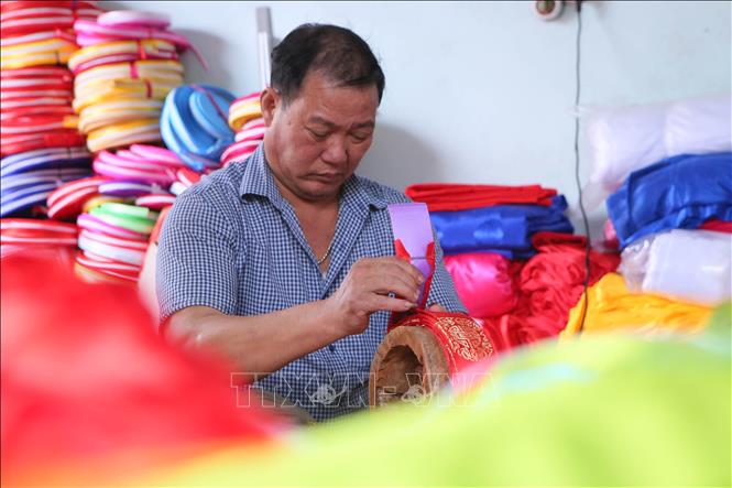 Anh Đoàn Văn Hữu, người dân làng Giáp Nhất thực hiện công đoạn bọc vành ngoài khăn xếp. Ảnh: Công Luật-TTXVN