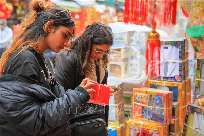 Du khách nước ngoài chọn mua lì xì trên phố Hàng Mã. Ảnh: Hoàng Hiếu - TTXVN