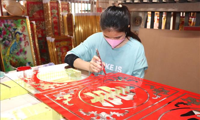 Nghệ nhân trang trí, sơn mặt sau tranh kính. Ảnh: Thanh Sang –TTXVN