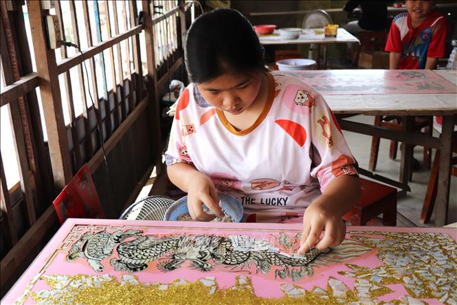 Công đoạn cẩn xà cừ trên tranh kính. Ảnh: Thanh Sang – TTXVN
