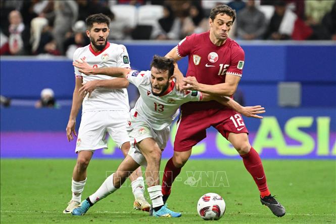 Pha tranh bóng giữa tiền vệ Tajikistan Amadoni Kamolov (giữa) với Lucas Mendes của Qatar (phải) trong trận đấu. Ảnh: AFP/TTXVN
