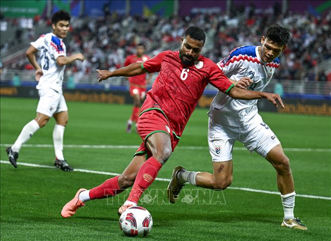 Pha tranh bóng giữa cầu thủ Supachai Chaided (phải) tuyển Thái Lan và Ahmed Al-Khamisi tuyển Oman. Ảnh: THX/TTXVN