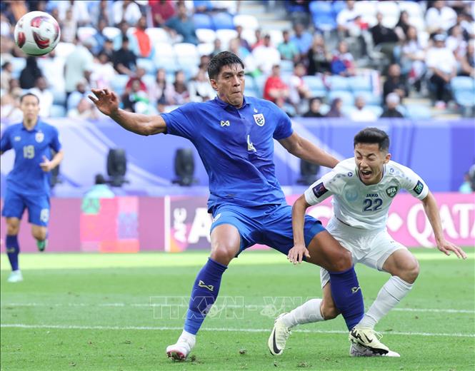 Pha tranh bóng giữa hậu vệ Thái Lan Elias Dolah (trái) với tiền vệ Rustamjon Ashurmatov (phải) của Uzbekistan. Ảnh: THX/TTXVN