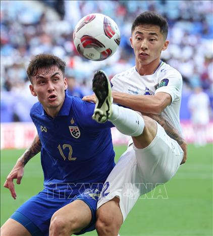 Pha tranh bóng giữa hậu vệ Thái Lan Look Saa Mickelson (trái) với tiền vệ Abbosbek Fayzullaev (phải) của Uzbekistan. Ảnh: THX/TTXVN