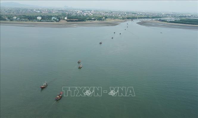 Tàu, thuyền của ngư dân ven biển huyện Diễn Châu nối đuôi nhau ra, vào cửa biển Lạch Vạn. Ảnh: TTXVN phát