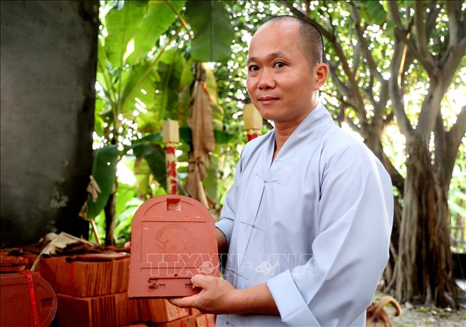 Đại đức Thích Nhuận Đạt giới thiệu ngói được in nổi hình Quốc huy Việt Nam, dùng để lợp mái chùa Trường Sa. Ảnh: Hồng Đạt - TTXVN
