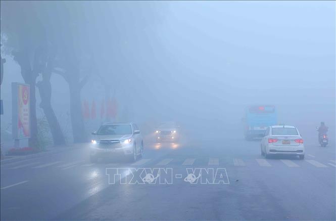 Các phương tiện di chuyển khó khăn trong lớp sương mù dày đặc trên phố Hoàng Diệu. Ảnh: An Đăng - TTXVN