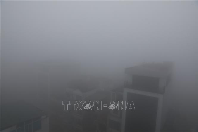 Các tòa nhà khu vực nội thành Hà Nội chìm trong làn sương mù dày đặc sáng 2/2. Ảnh: Huy Hùng - TTXVN