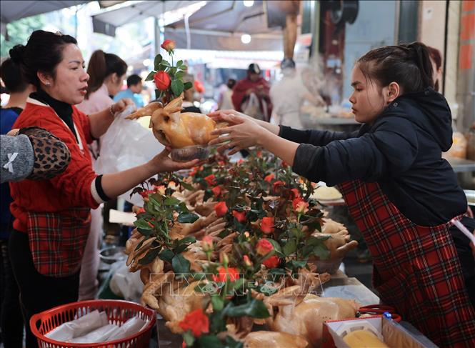 Ở các chợ trên địa bàn Hà Nội, gà luộc buộc cánh tiên, ngậm hoa được mua nhiều để cúng ông Công, ông Táo. Ảnh: Hoàng Hiếu - TTXVN 