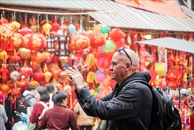 Du khách nước ngoài lưu lại không khí cận Tết tại chợ hoa Hàng Lược. Ảnh: Khánh Hoà - TTXVN