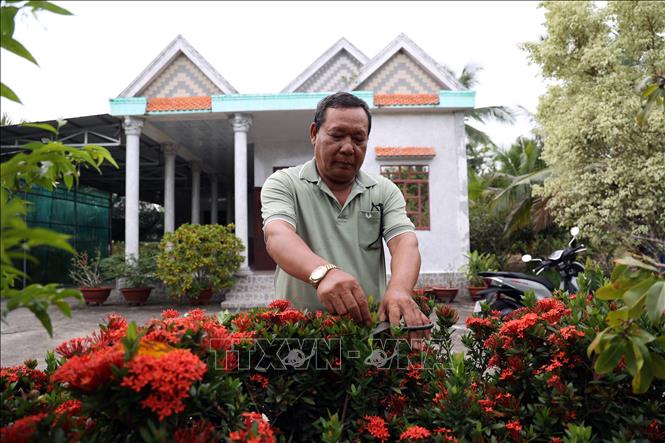 Ông Danh Út chăm sóc cây cảnh. Ảnh: Lê Sen - TTXVN
