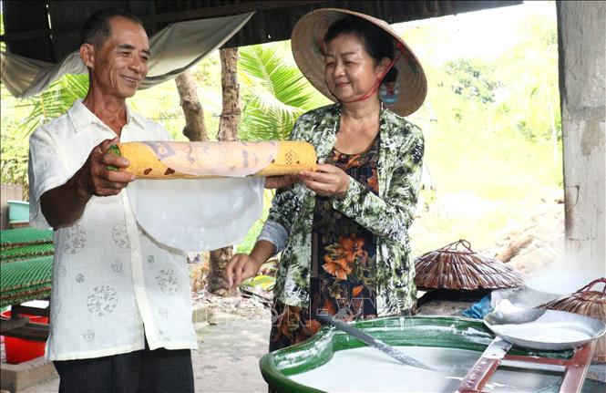 Bà Nguyễn Thị Lệ Hằng (xã Lục Sỹ Thành, huyện Trà Ôn, tỉnh Vĩnh Long)  cẩn thận lấy từng chiếc bánh tráng ra khỏi lò. Ảnh: Lê Thúy Hằng - TTXVN