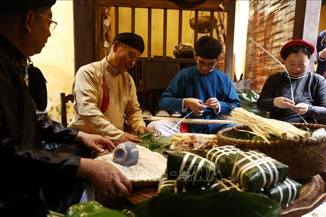 Thành viên CLB Đình làng Việt trong trang phục áo dài truyền thống cùng gói bánh chưng Tết. Ảnh: Minh Quyết – TTXVN