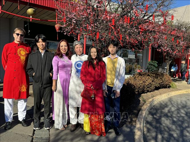 Gia đình chị Thảo anh James chụp ảnh bên cây đào cảnh tại khu chợ Việt. Ảnh: Kiều Trang - PV TTXVN tại Mỹ